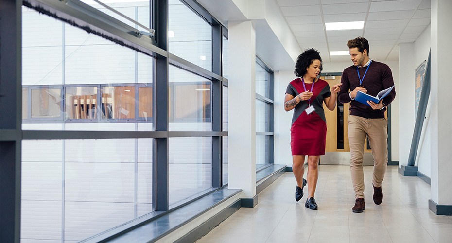 substitute teacher walking with and getting instructions from another teacher on her way to class