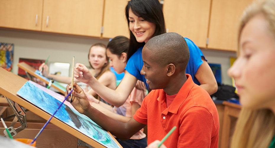 high school art teacher helps students in painting class