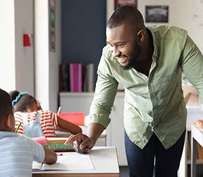 elementary school teacher talks to student in class