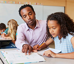 teacher helps young student with her schoolwork