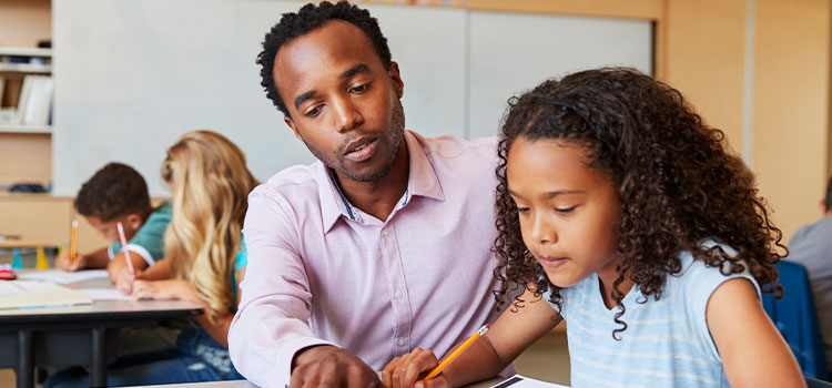 teacher helps young student with her schoolwork