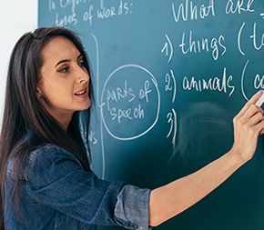 substitute teacher writes about parts of speech on blackboard